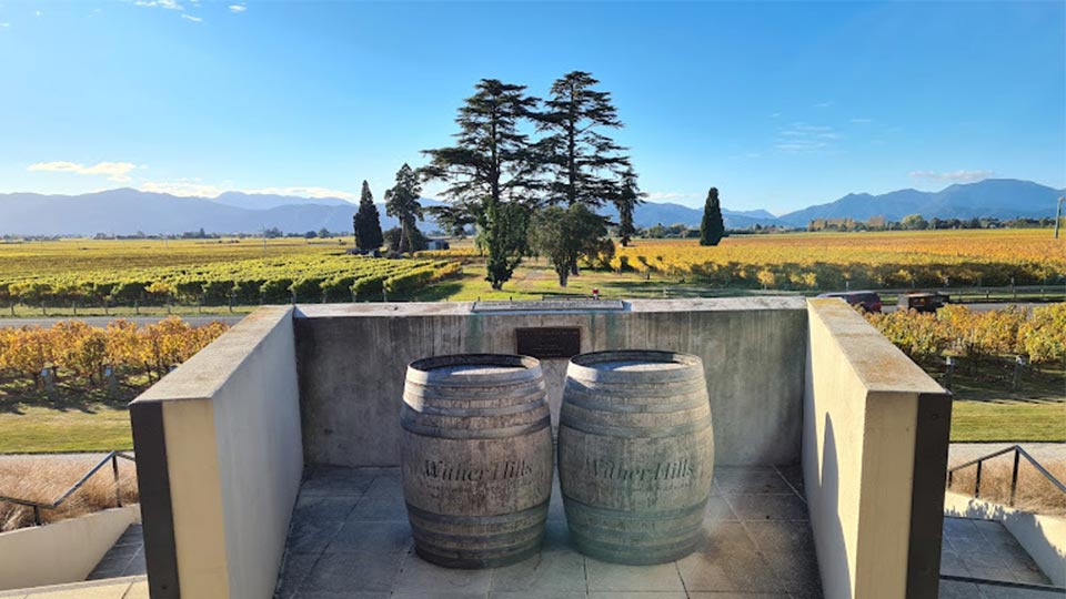 2 wine barrels in an alcove with the vineyard, trees and mountains in the background