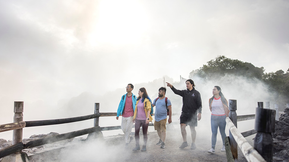 A group of 5 walking down the designated path through the thermal rocks that are letting off sulphur