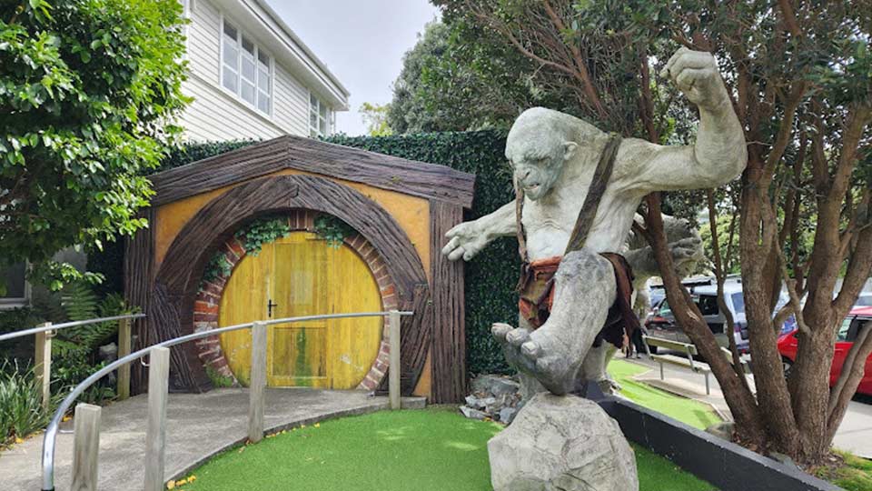A statue of an Orc from Lord of The Rings with his fist raised in front of the entrance to Weta Workshop
